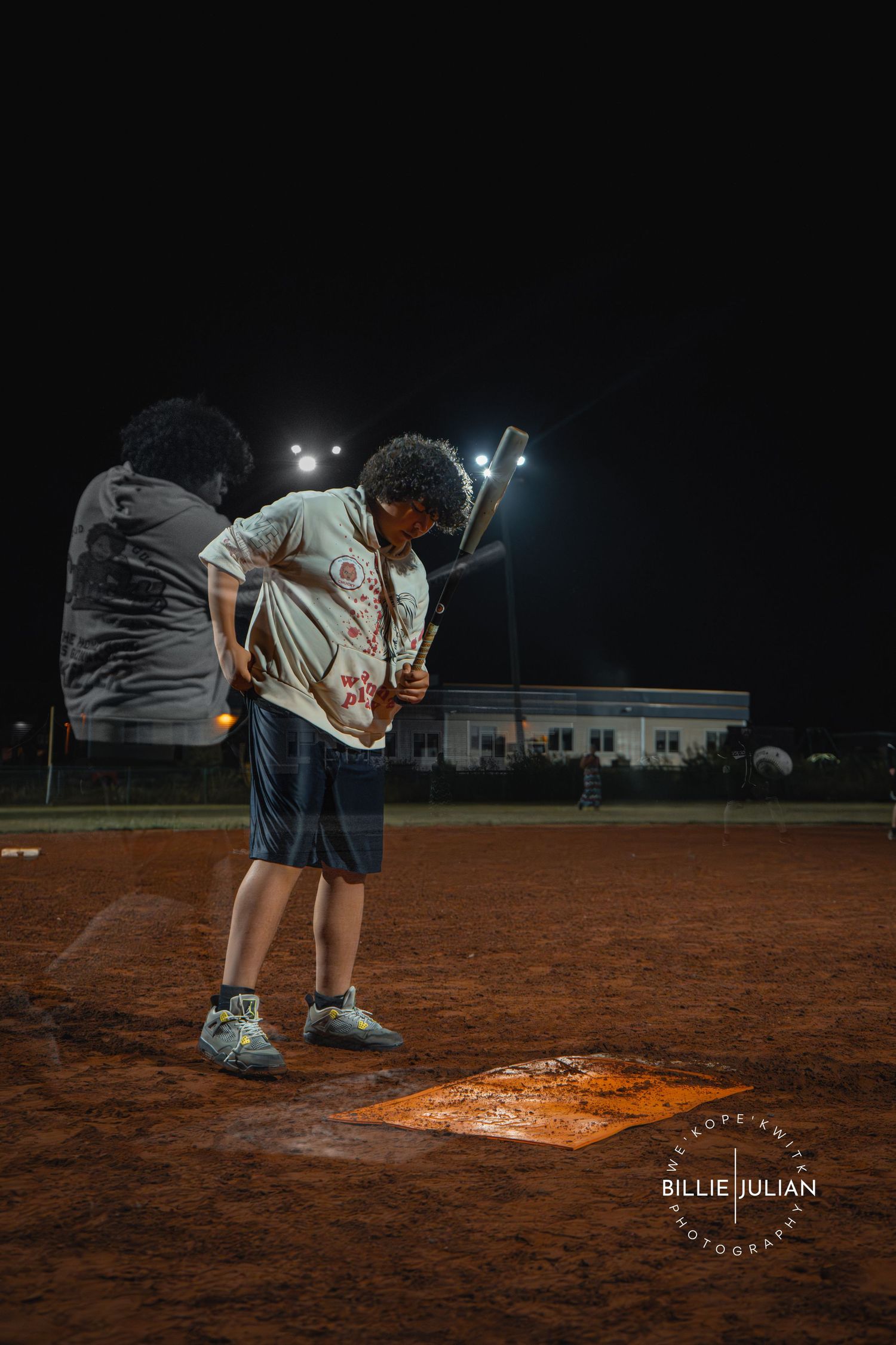 Close-up view of players near illuminated base during nighttime softball game.