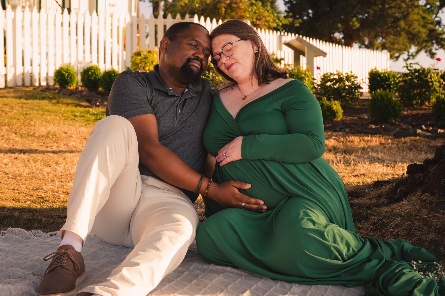 A couple shares a romantic moment together on a bench during sunset in an outdoor setting.
