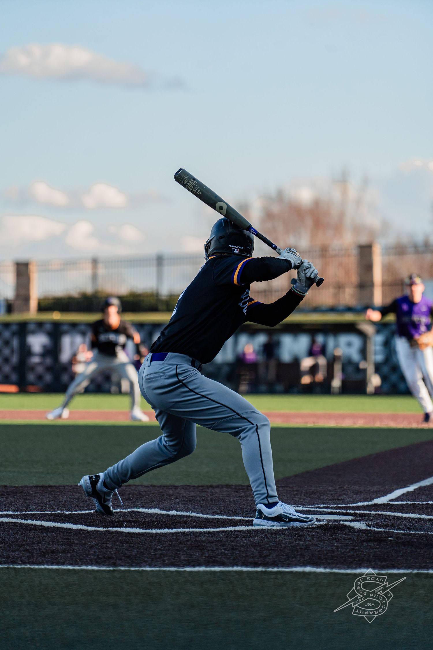 Baseball batter in motion swings at home plate during a daytime game.