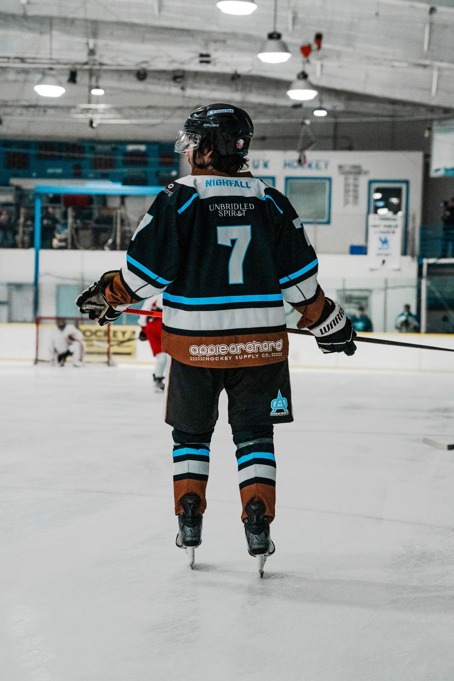 Hockey players in light blue jerseys skating on an indoor ice rink.