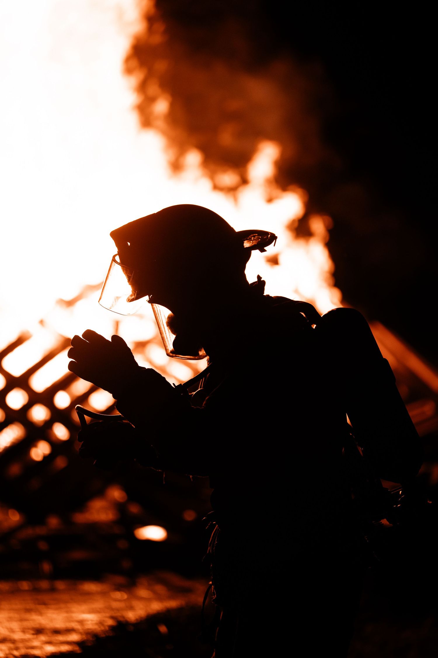 Dramatic silhouettes of firefighters battling flames against a dark night sky.