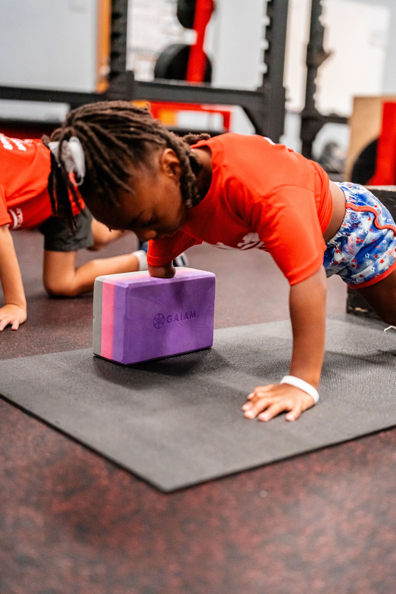 Athletes perform pushups using purple yoga blocks during indoor training.