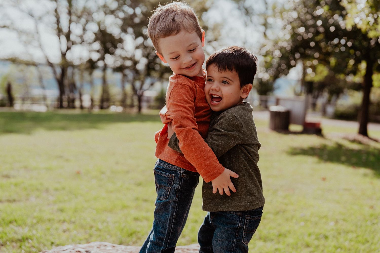Children playing and running together on grass in a park setting.