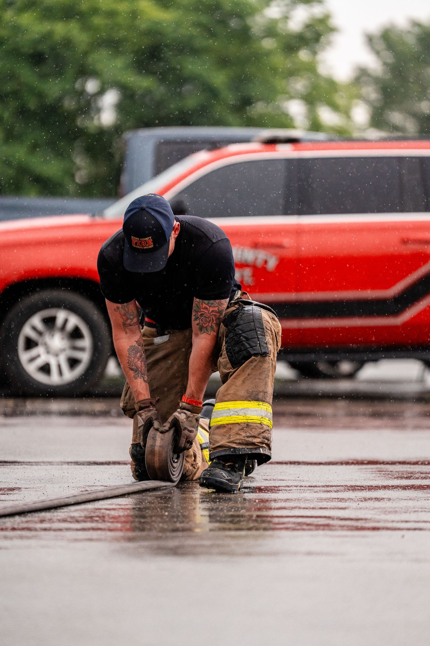 Low angle view of firefighters crawling across wet pavement during an emergency response drill.