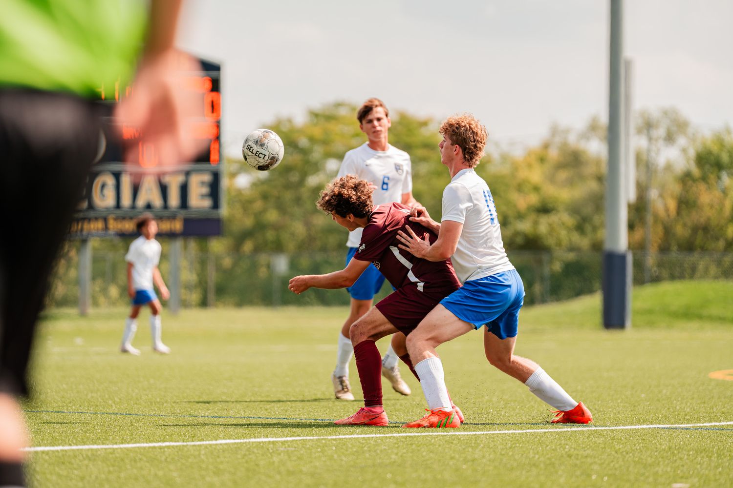 Soccer players compete for ball possession during match on grass field.