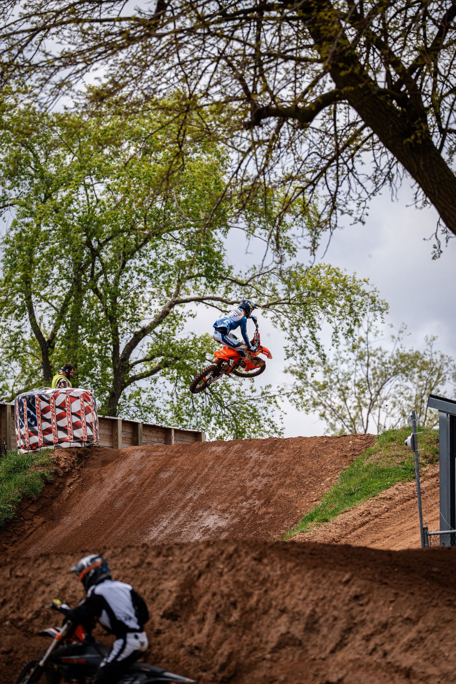 Dirt bike rider jumping over a steep hill track during a race.