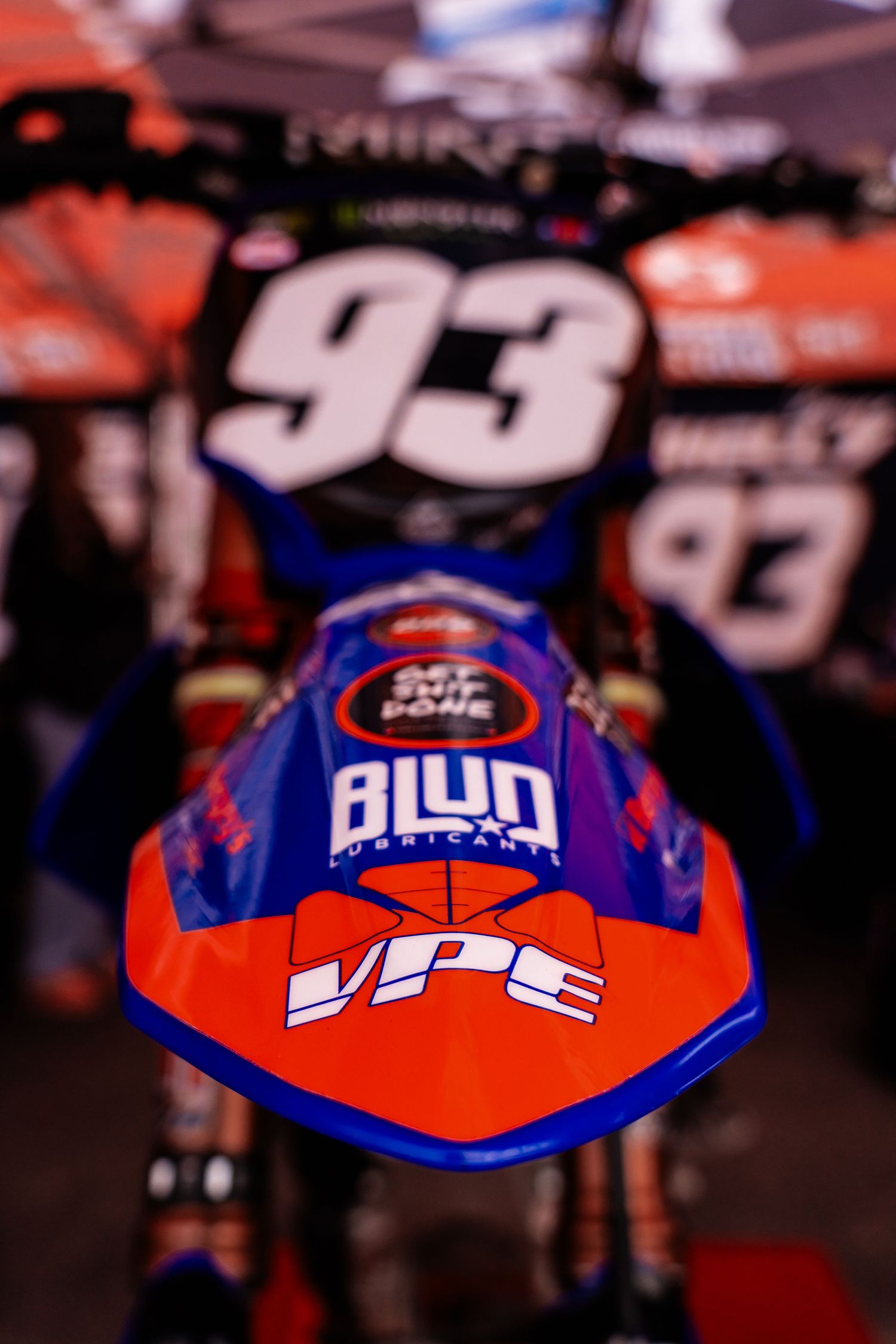 Racing bike helmets in red and blue colors with sponsor logos and branding.