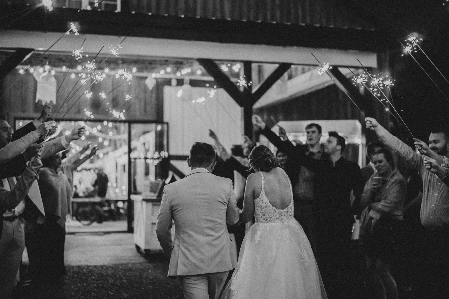Wedding reception venue at night with string lights and guests mingling.