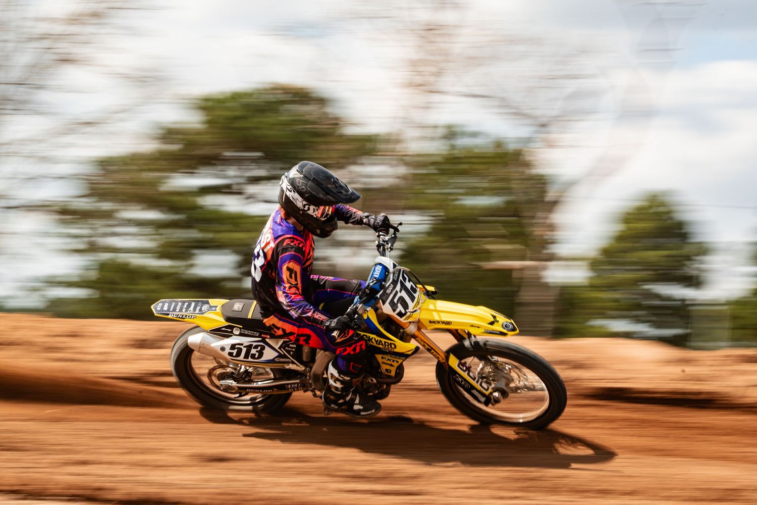 A dirt bike rider navigates a dusty, off-road track with speed and agility.
