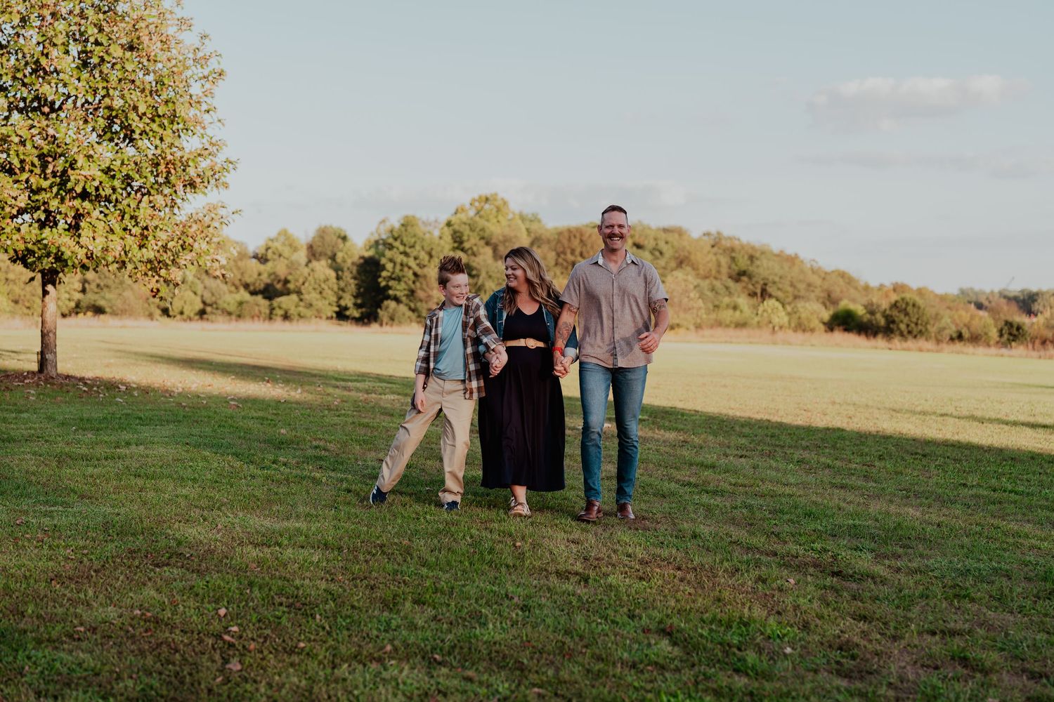 Family walking together across a scenic grassy field at sunset.