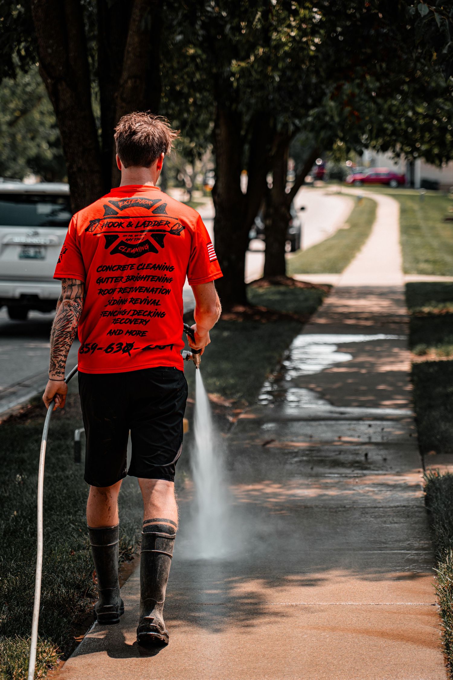 Person in red shirt walking on a wet pathway during an outdoor event.