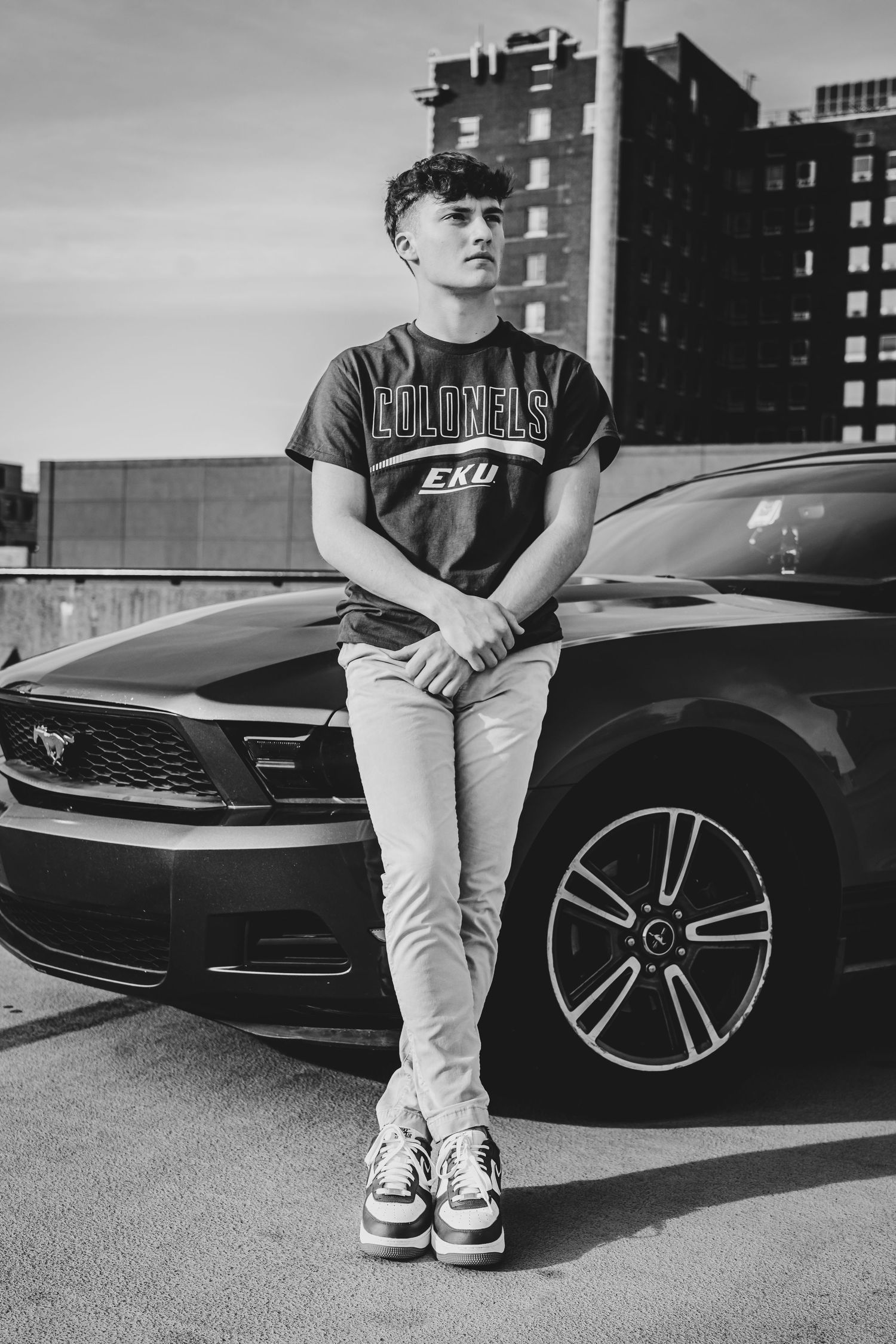Black and white photo series showing casual attire against a sleek black car in an urban setting.