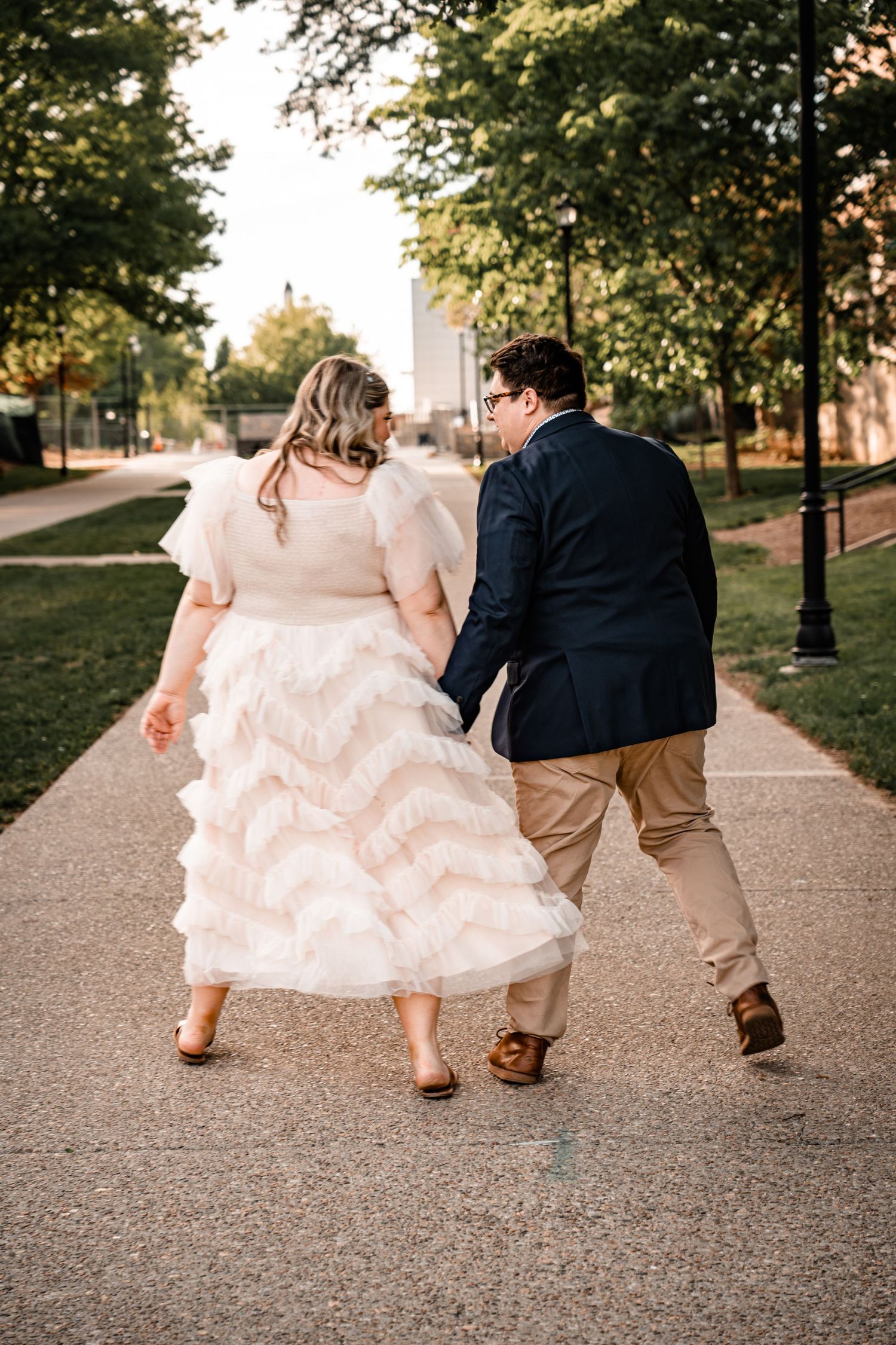 Formal shoes walking together on a paved path during sunset.