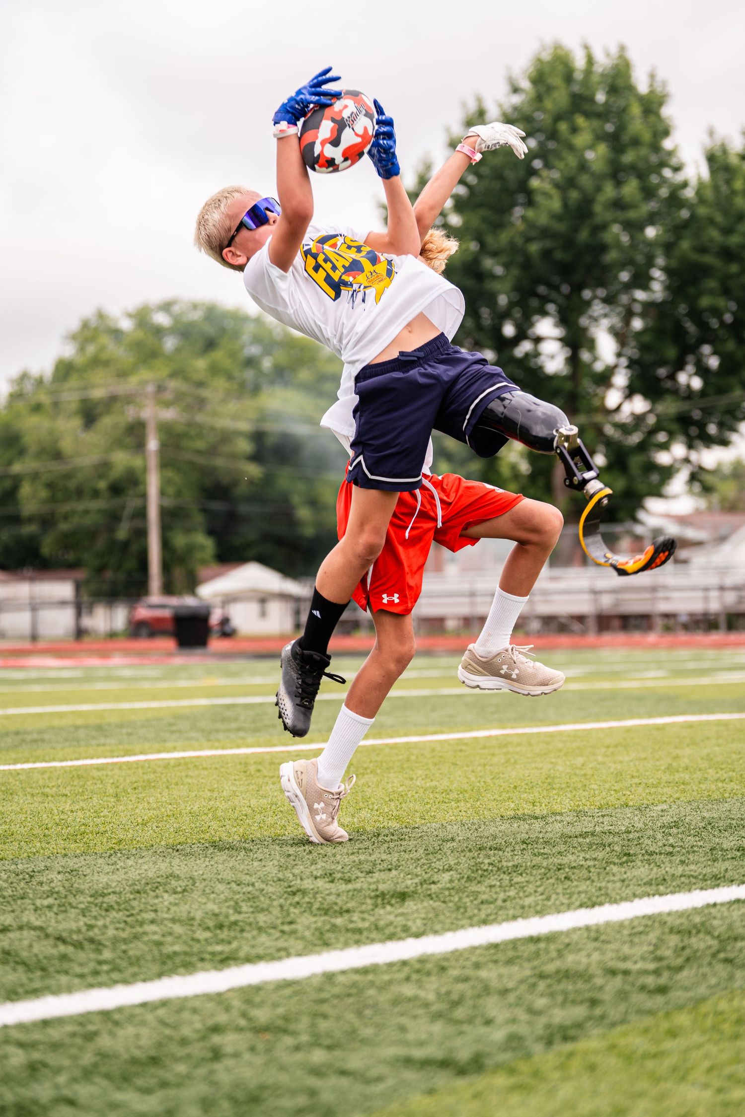 Athletes perform dynamic jumping exercises on an outdoor sports field.
