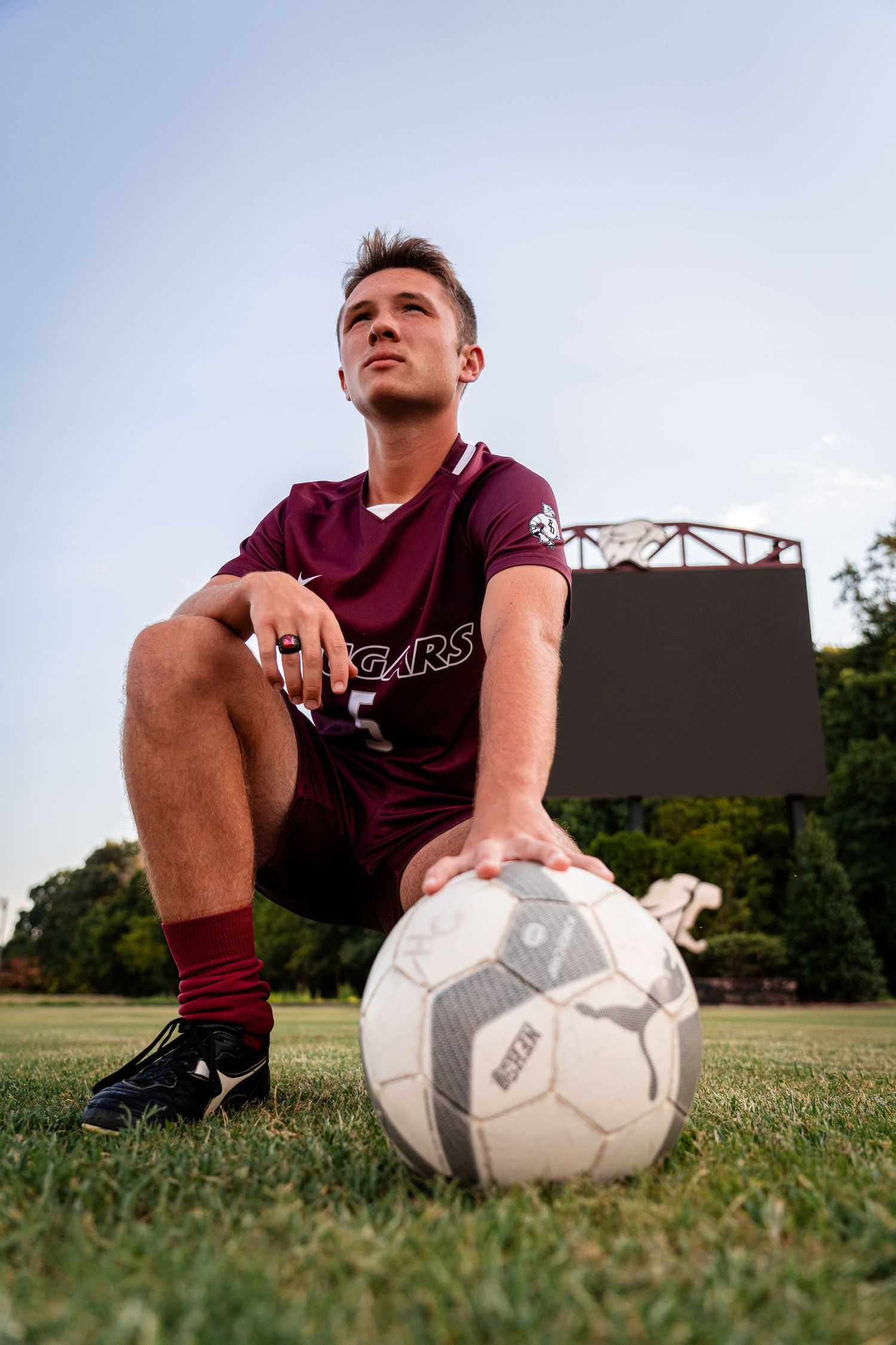 Soccer player sitting on grass field with white soccer ball.