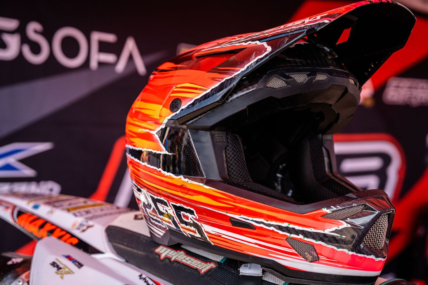 Close-up details of red motorcycle helmets and racing gear displayed at a motorsports event.
