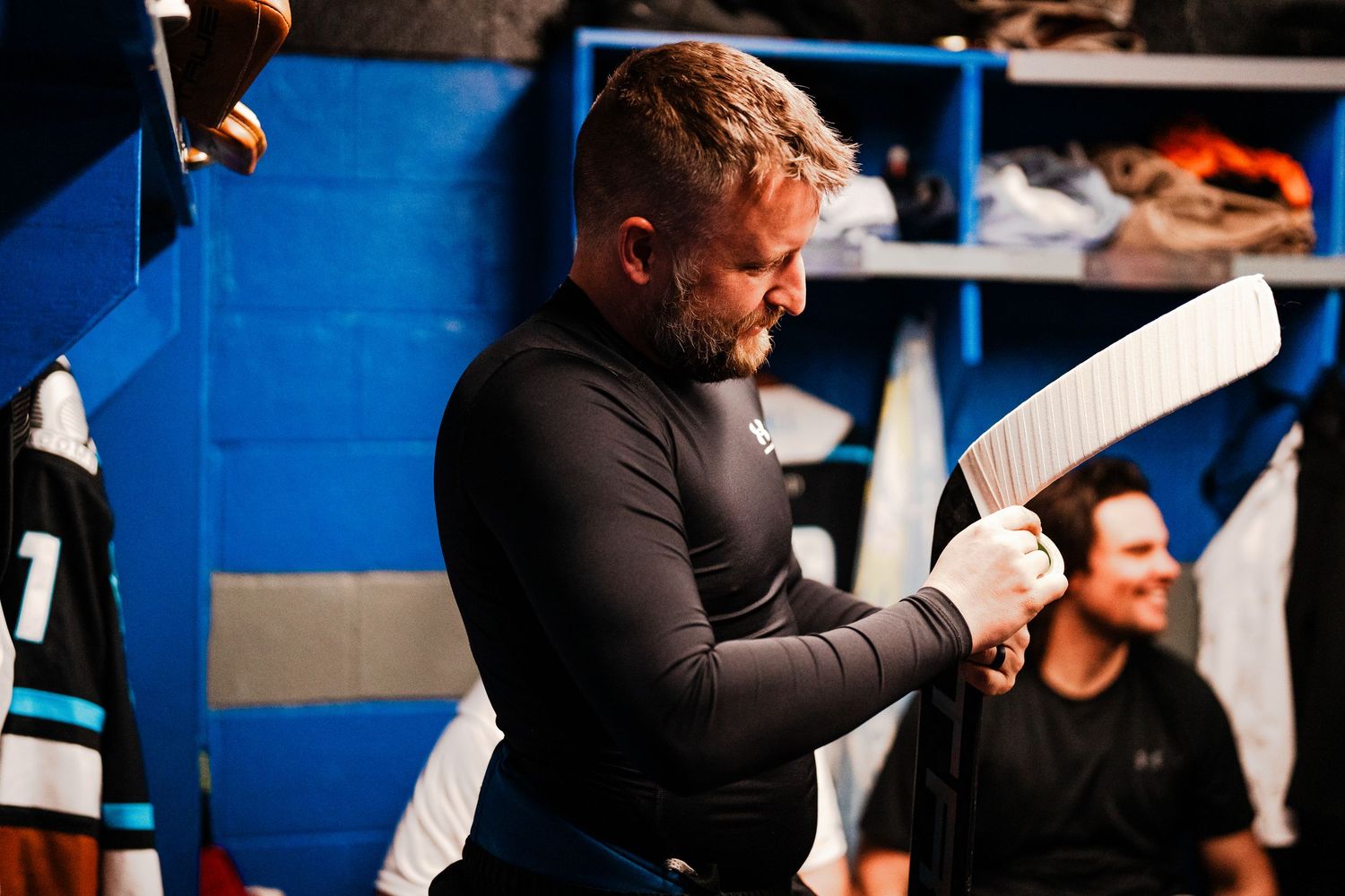 A man in a black outfit is shown working on something in a workshop setting.
