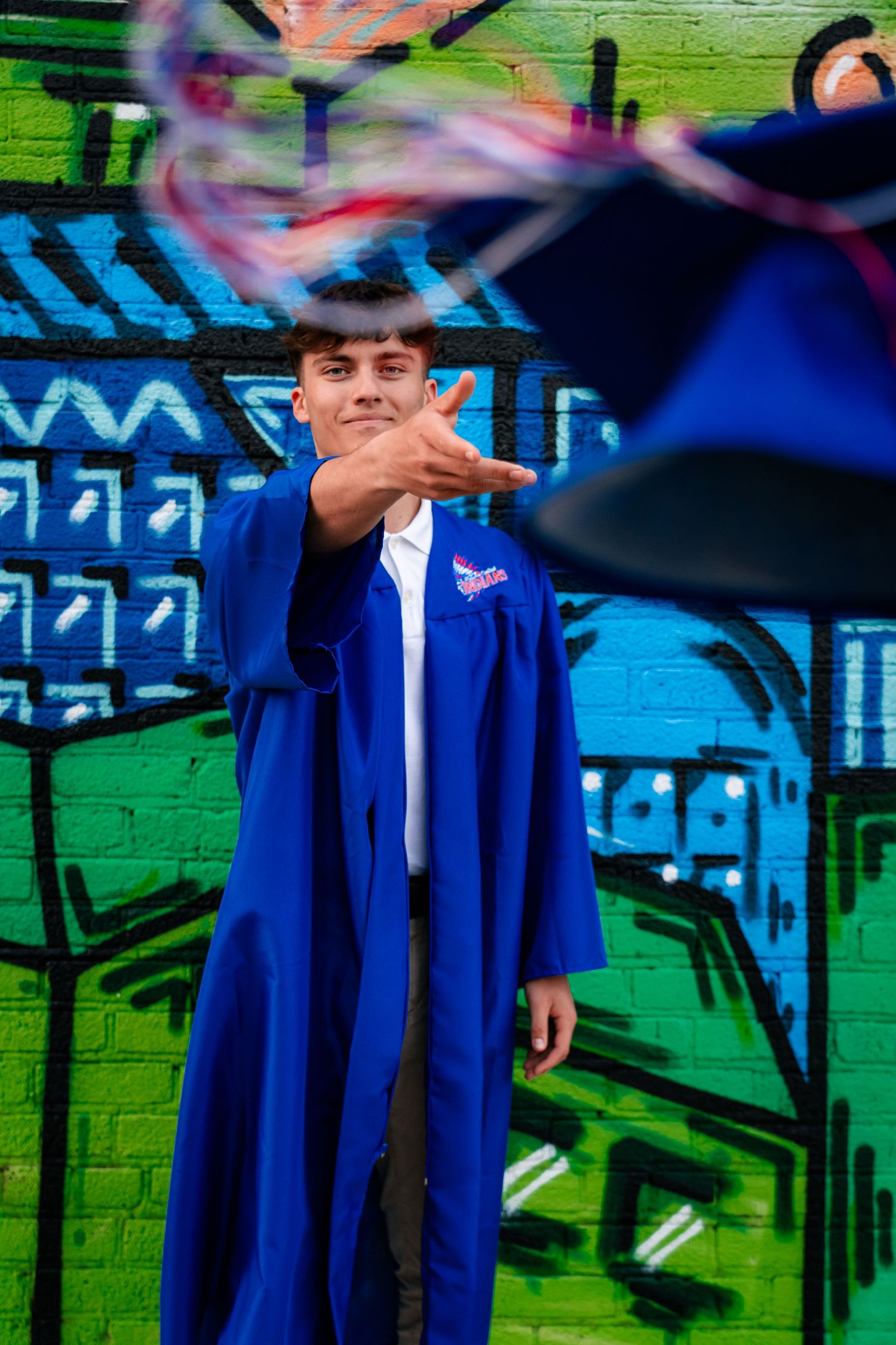 Artistic photo series featuring vibrant graffiti wall with blue graduation gown.