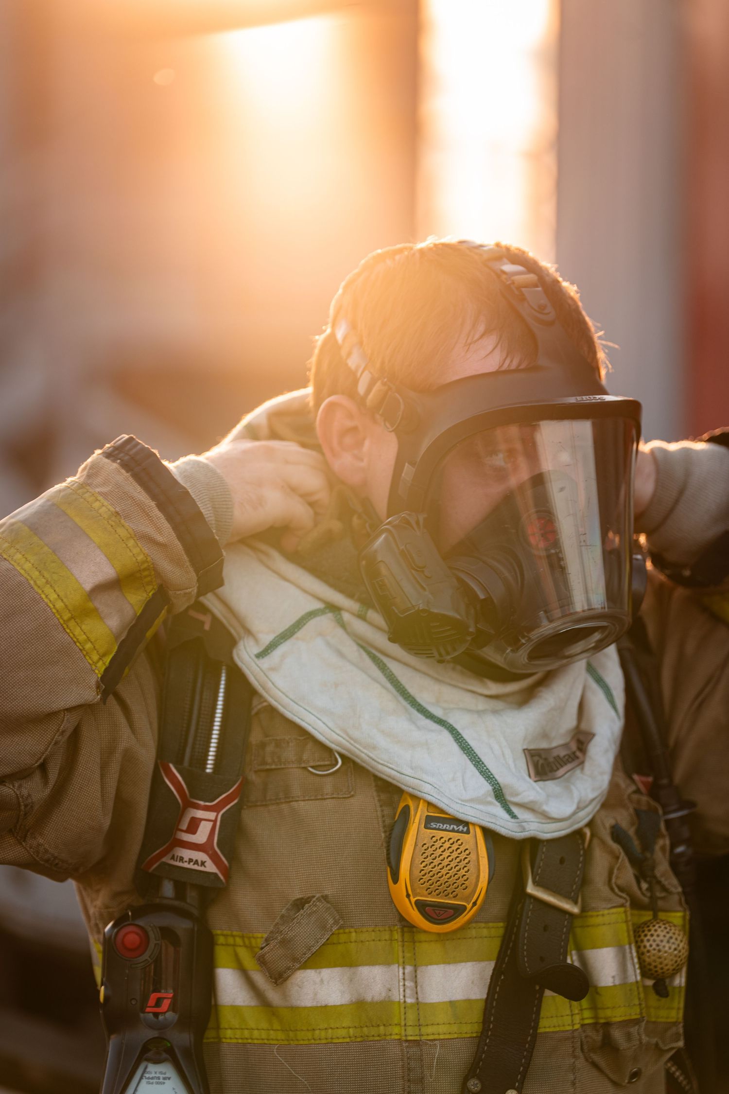 Silhouette of firefighters in protective gear backlit by golden sunset light during training.