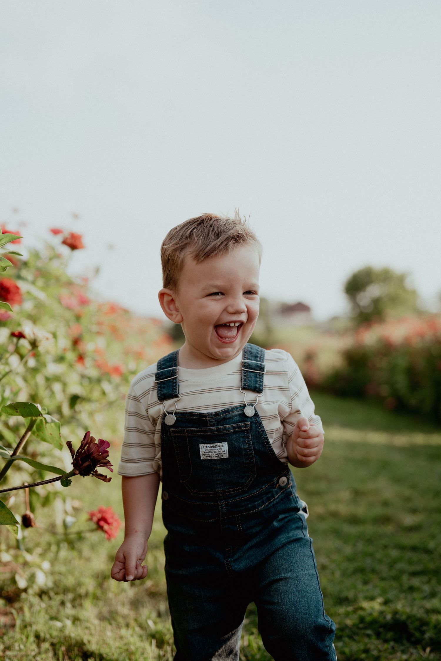 Joyful laughter in overalls against a backdrop of blooming flowers.
