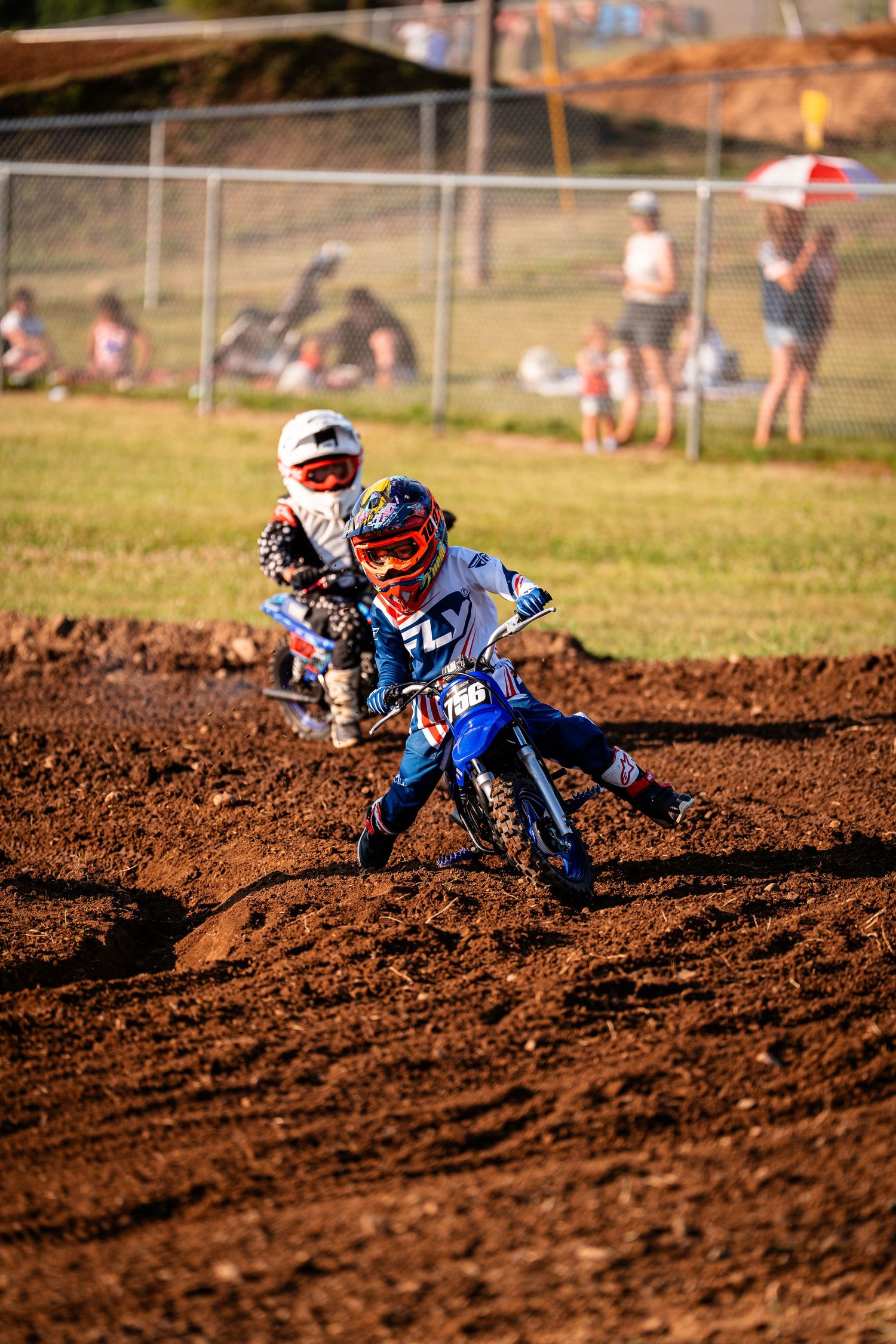 Motocross rider leans into turn on dirt track during competitive race.
