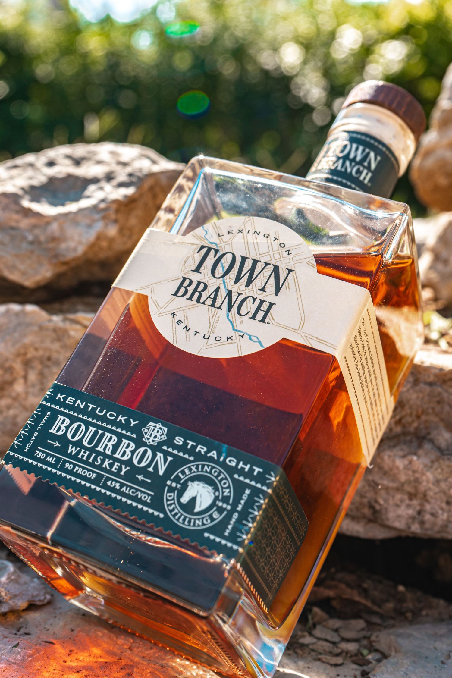 Town Branch bourbon bottles displayed on rocky terrain in natural sunlight.