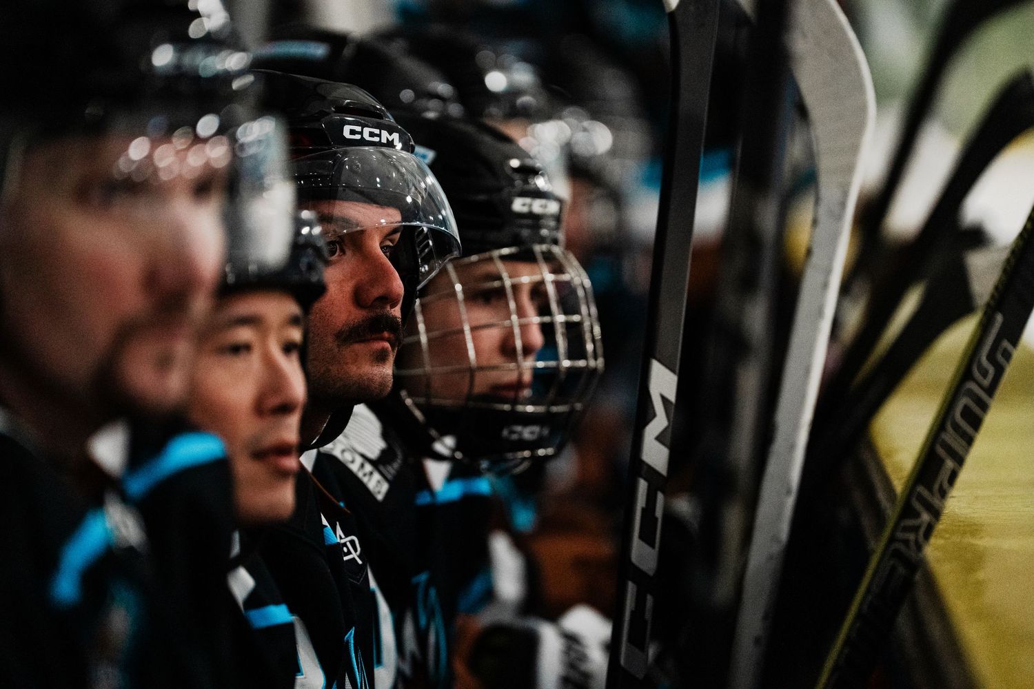 A close-up view of hockey players wearing helmets and uniforms, focused intently on the game.