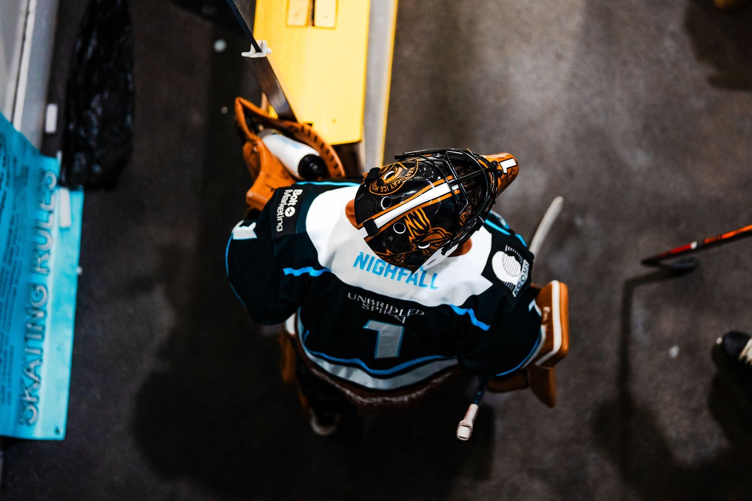 Hockey players in black and blue uniforms skating on ice during a game.