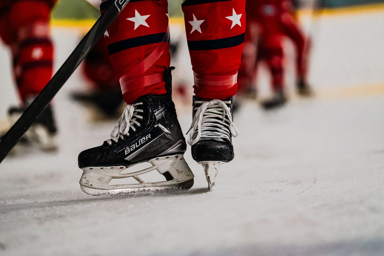 Close-up of hockey skates and equipment on ice during game play.