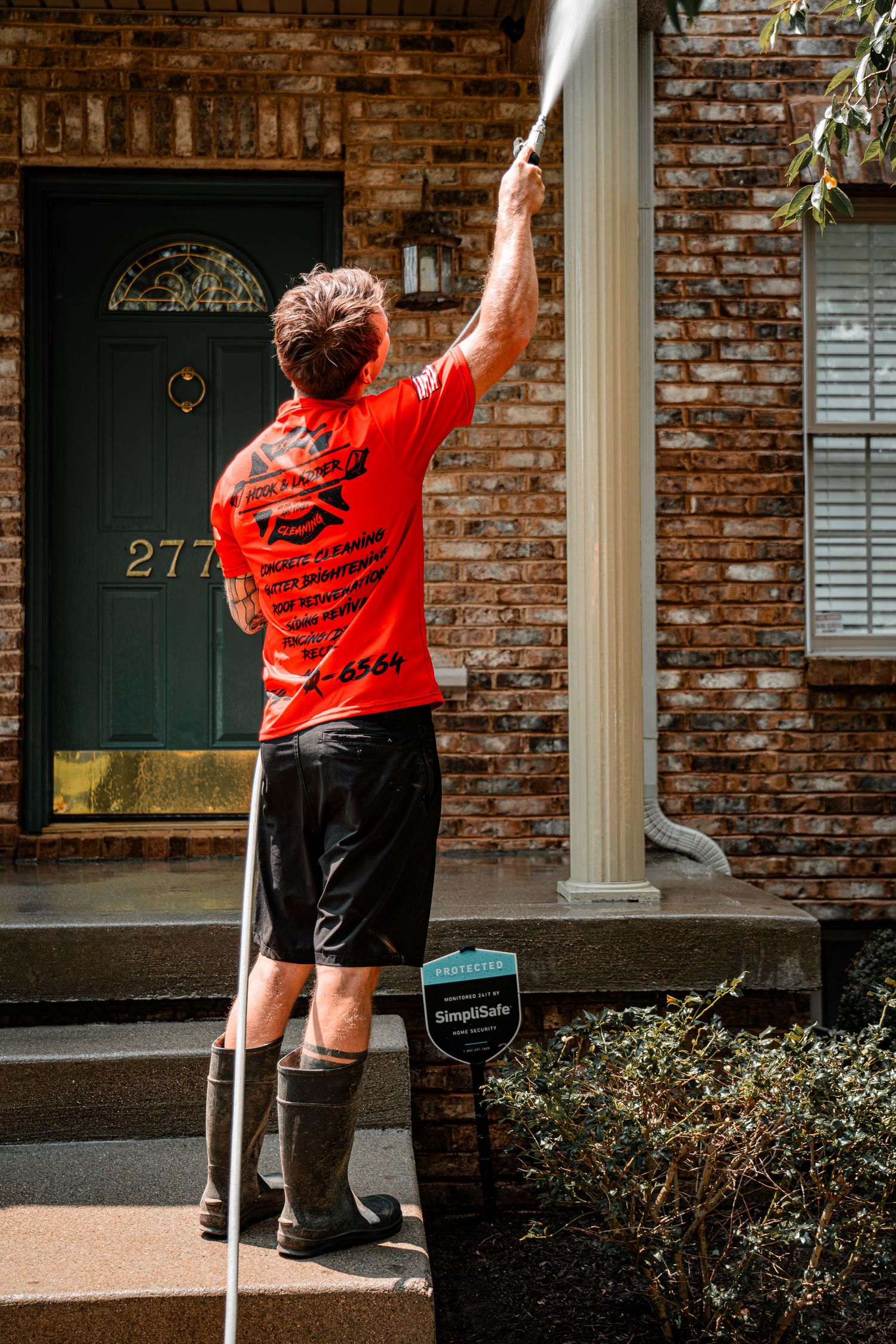 Staff member in red shirt waving while walking past brick buildings.