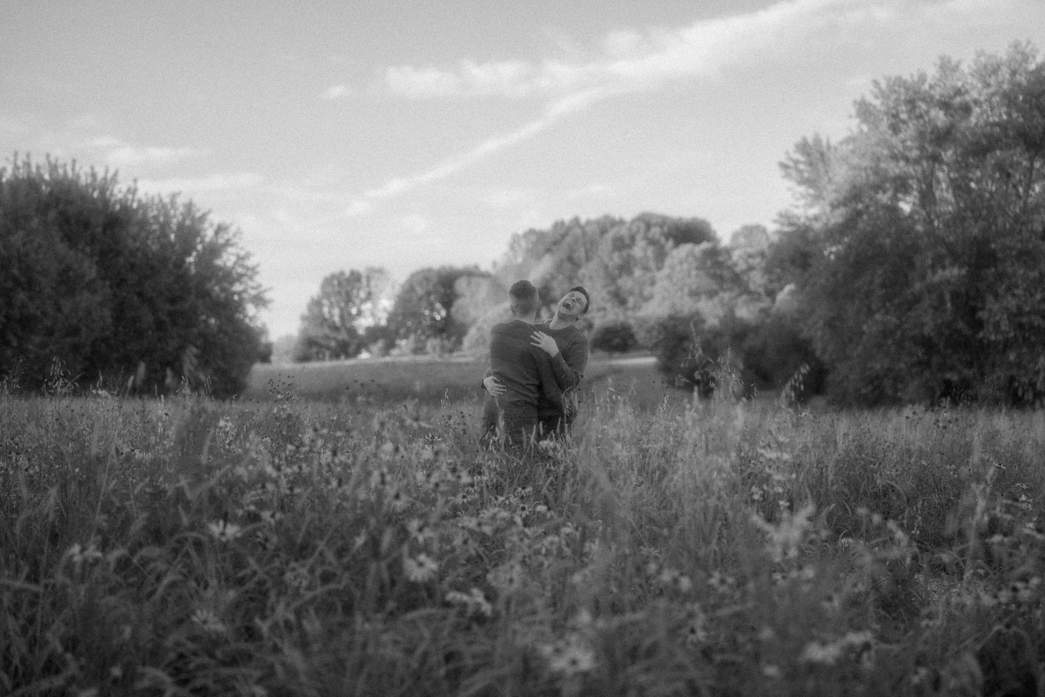 Black and white panoramic landscape of a rural field with trees in the distance.