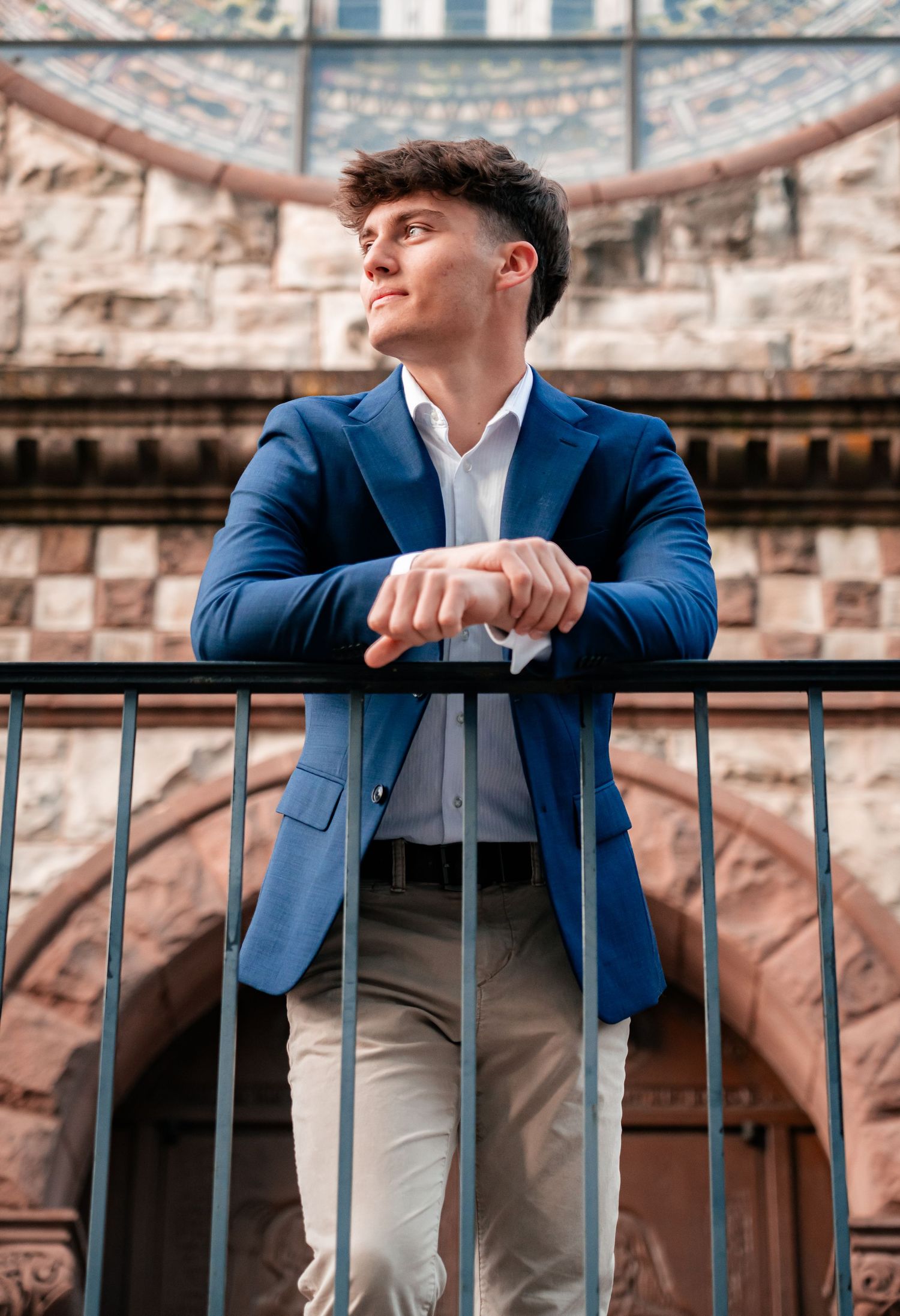 Formal portrait series showing blue suit and railing against architectural backdrop.