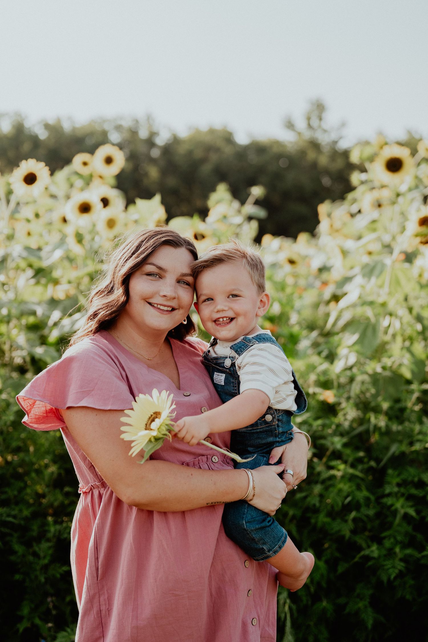 A tender moment captured in a sunflower field with warm lighting and natural expressions.