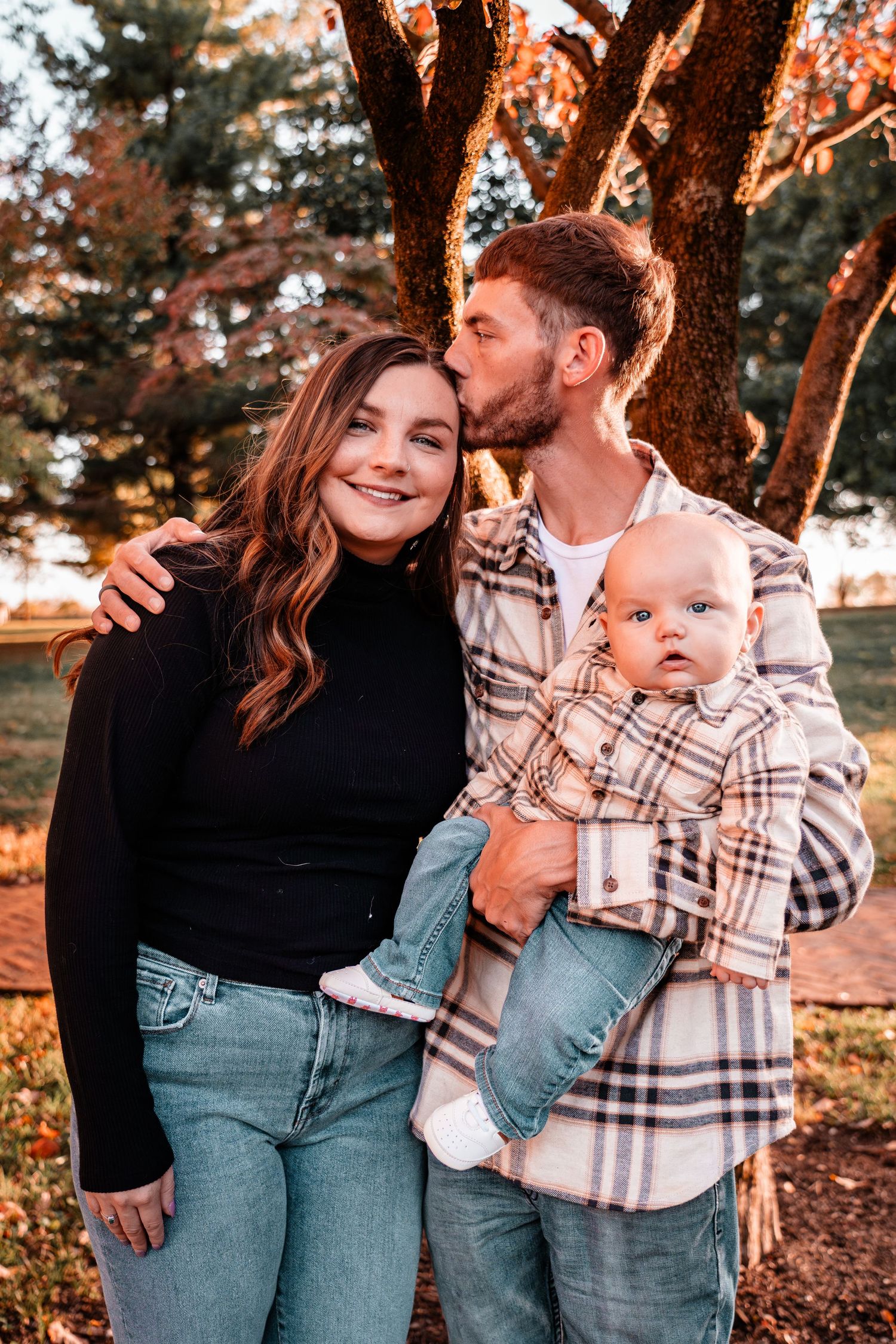 A cozy autumn family portrait with fall foliage and warm lighting in the background.