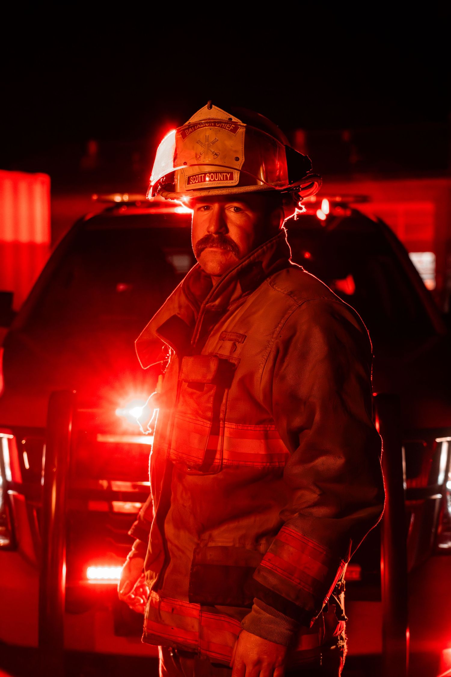 Emergency responders illuminated by red lights at a nighttime scene.