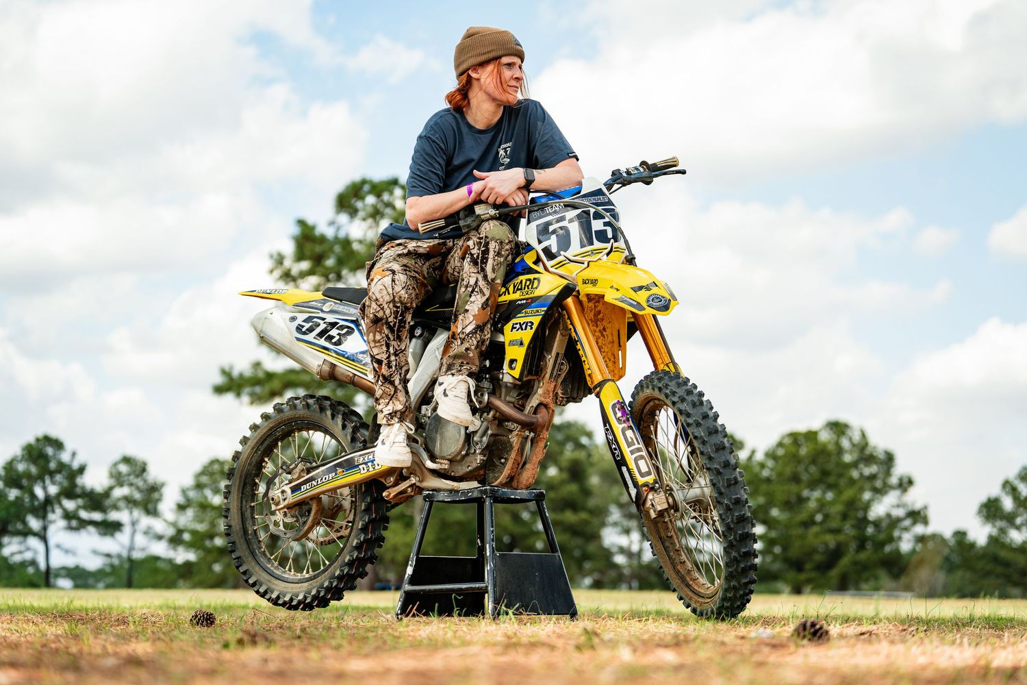 A person riding a yellow and black dirt bike on a dirt track surrounded by trees.