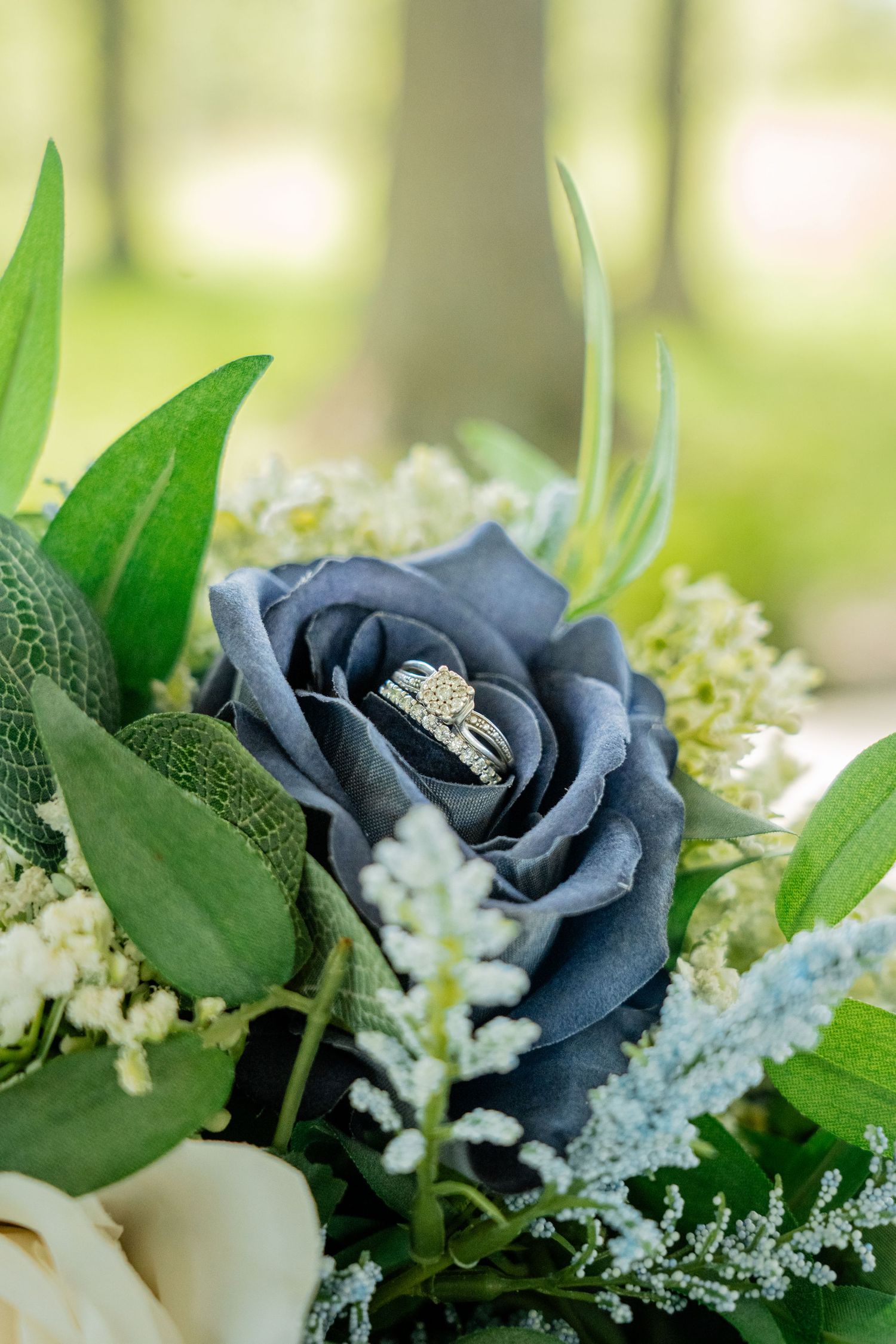 Elegant blue roses and white flowers arranged with delicate greenery in a wedding bouquet.