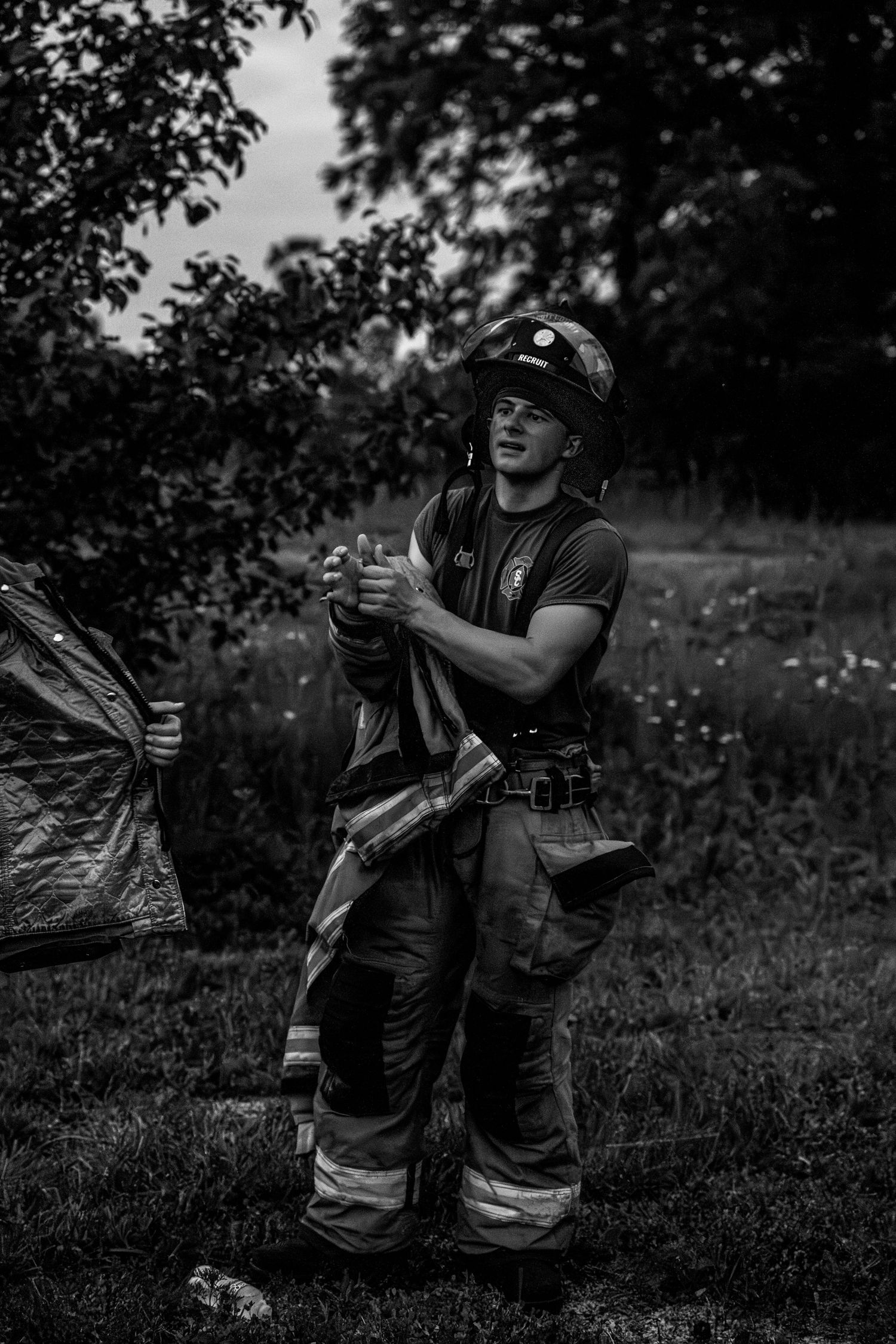 Firefighter in full gear resting on grass after an operation.
