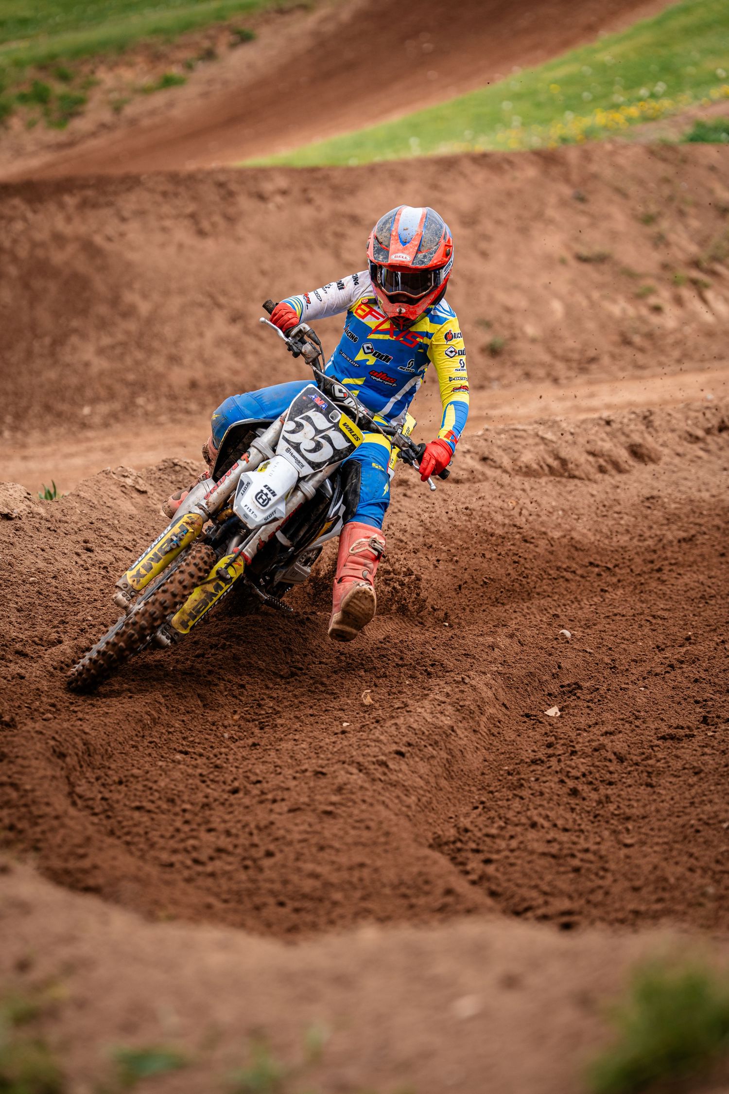 Motocross riders leaning into dirt track turn during competitive race.