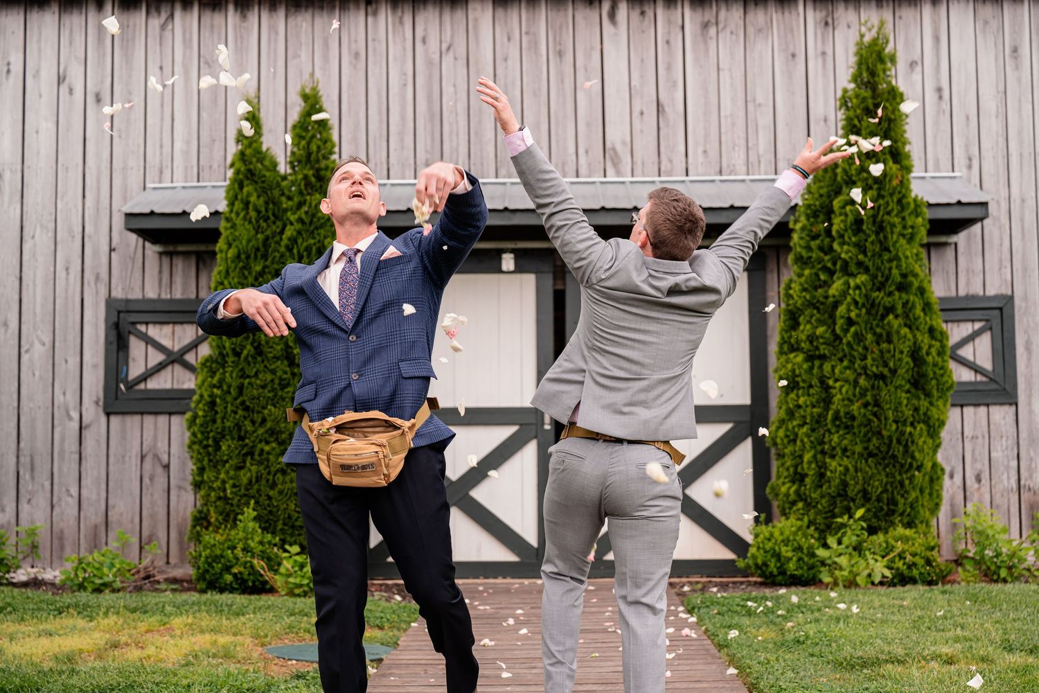 Wedding guests throwing confetti and celebrating outside rustic barn venue.