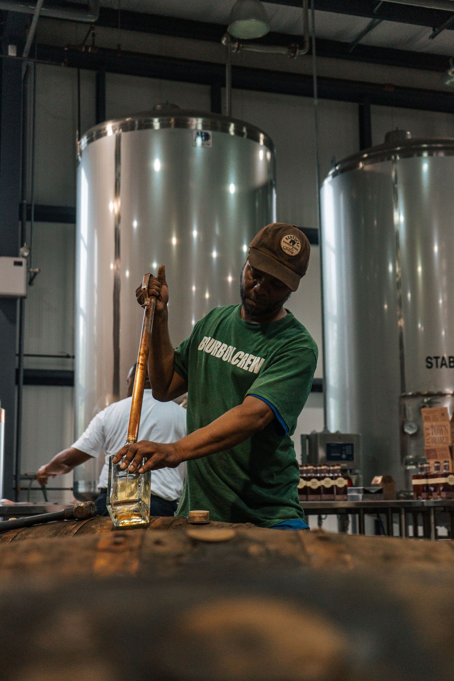 Distillery worker checking fermentation tanks in a modern production facility.