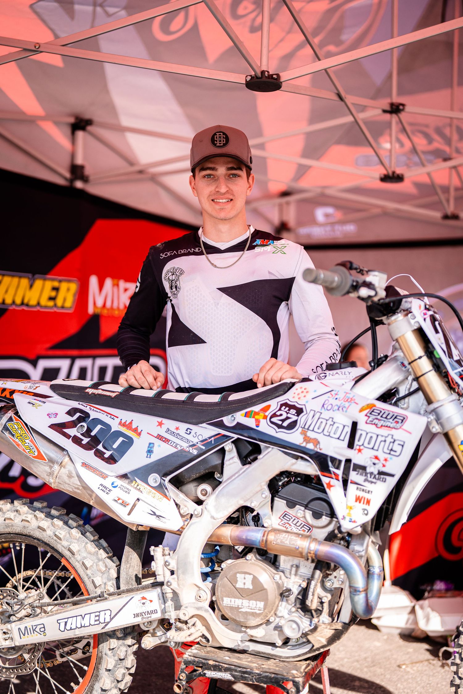 Custom racing dirt bikes lined up under a white tent at a motorsports event.