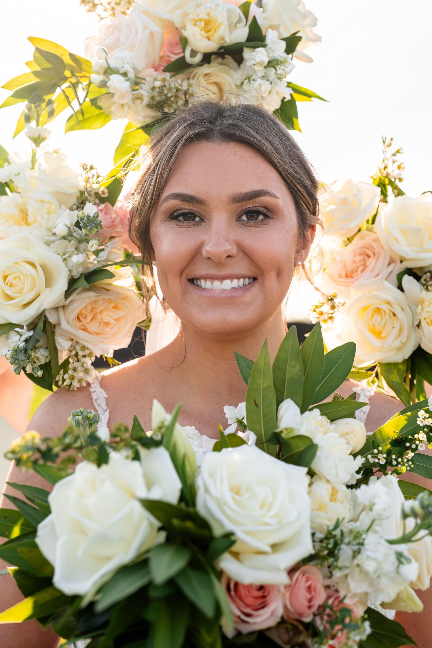 A bridal bouquet of white roses and peach blooms frames a joyful moment.