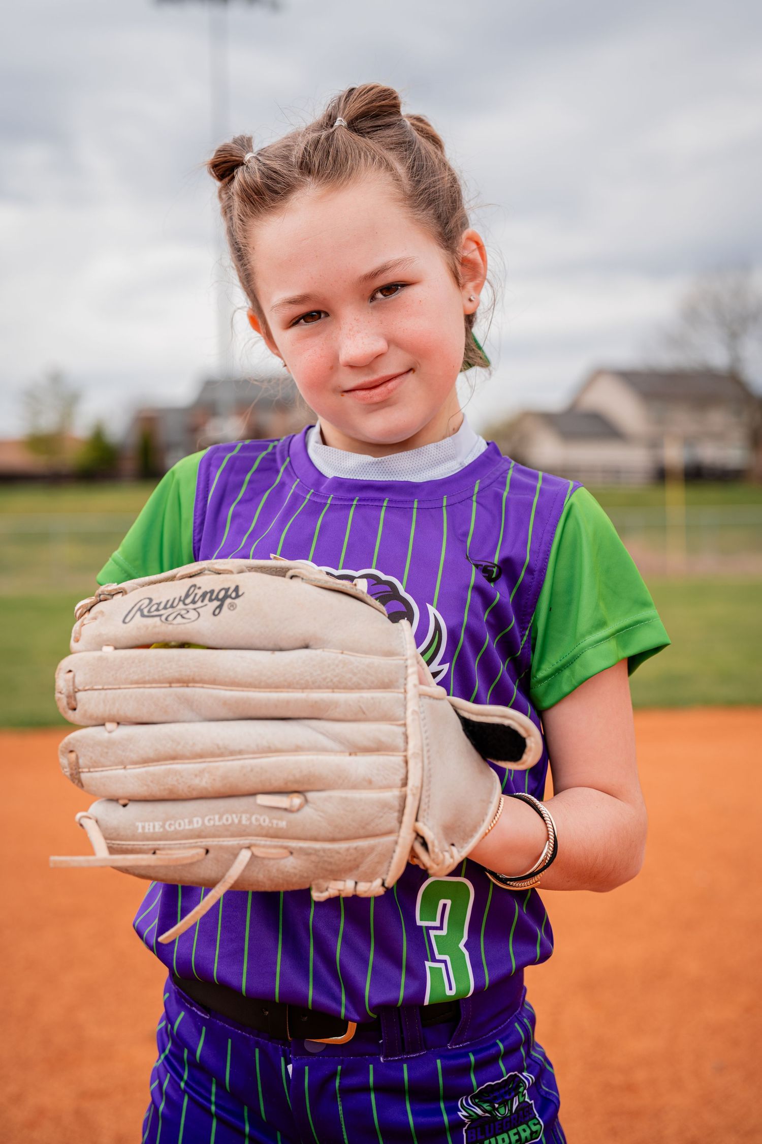 Young athlete in purple pinstriped uniform poses with baseball glove.