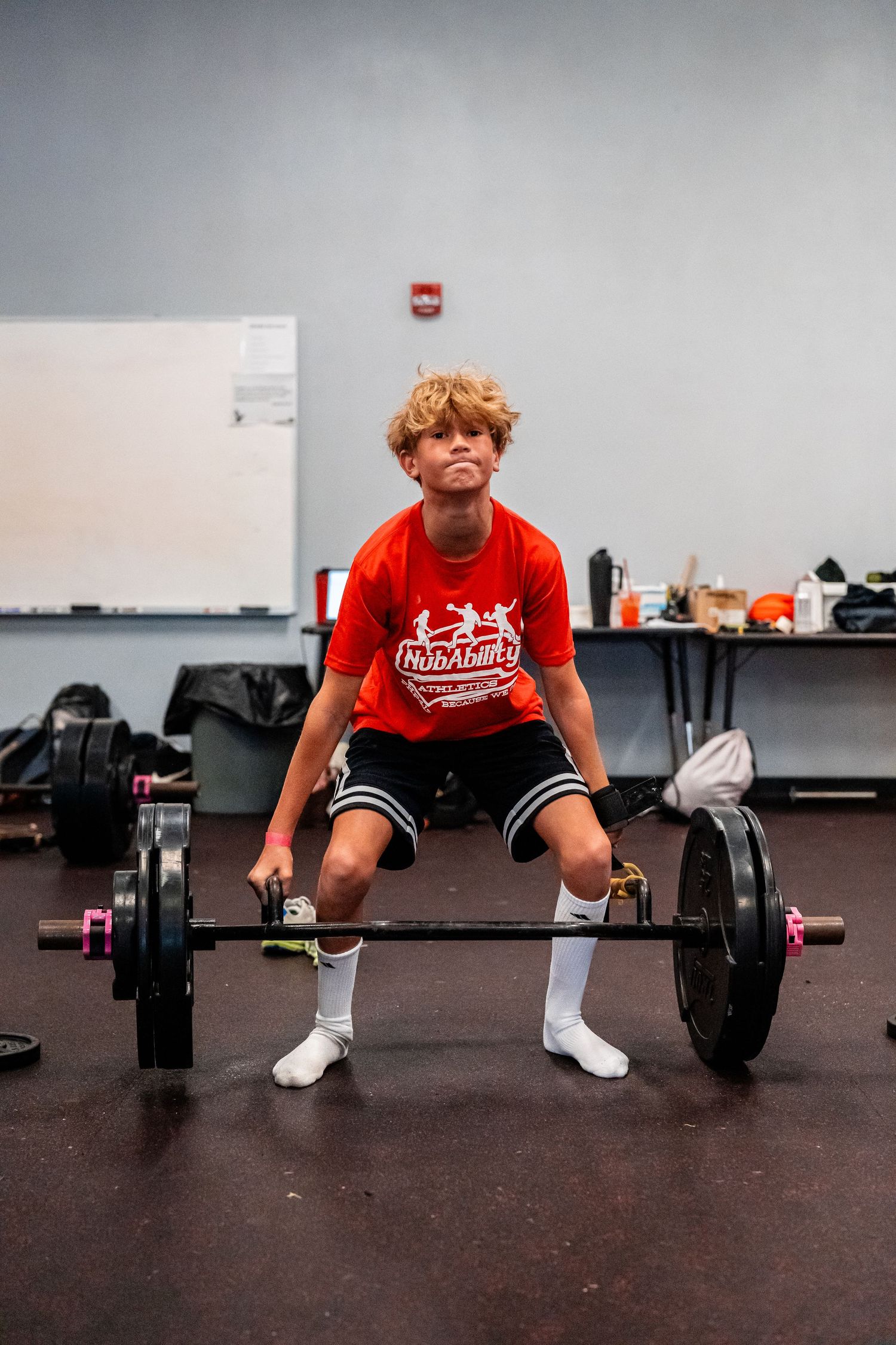 Athletes demonstrate proper deadlift form with barbells in a training facility.