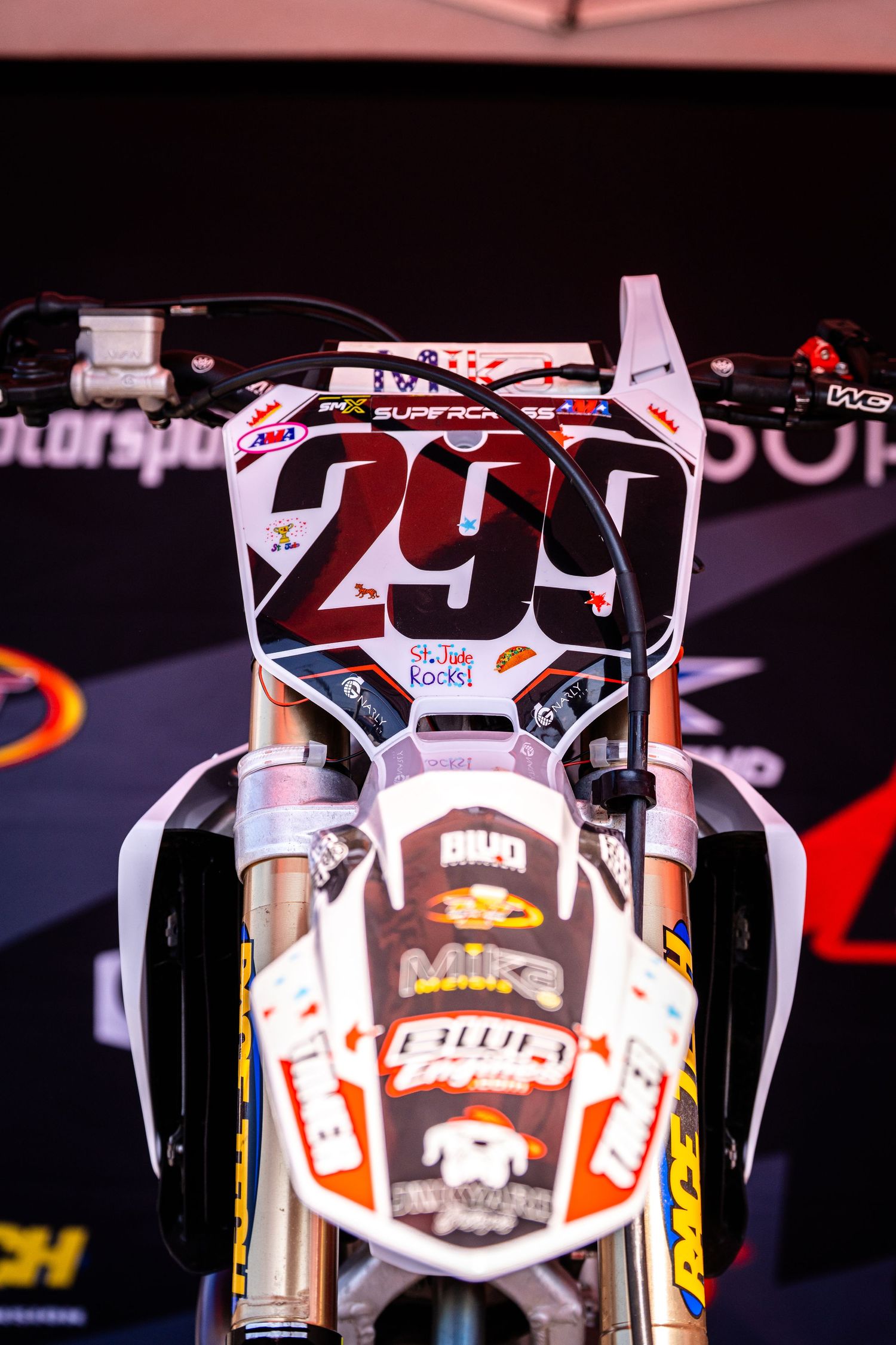Close-up of racing motorcycle number plates and graphics in dark lighting.