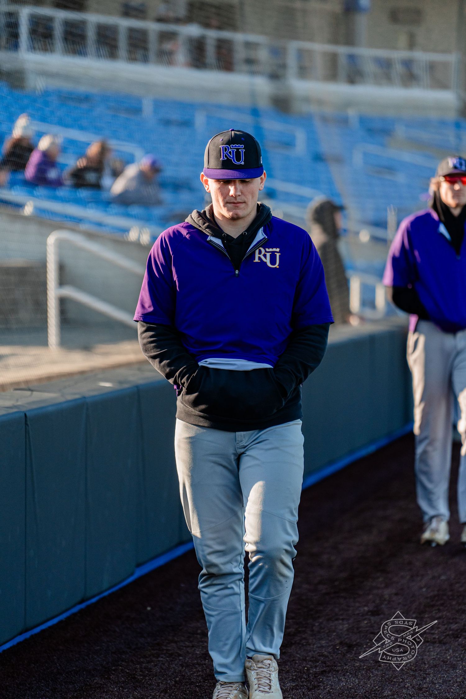 Baseball players in blue uniforms walk along the field during a game.