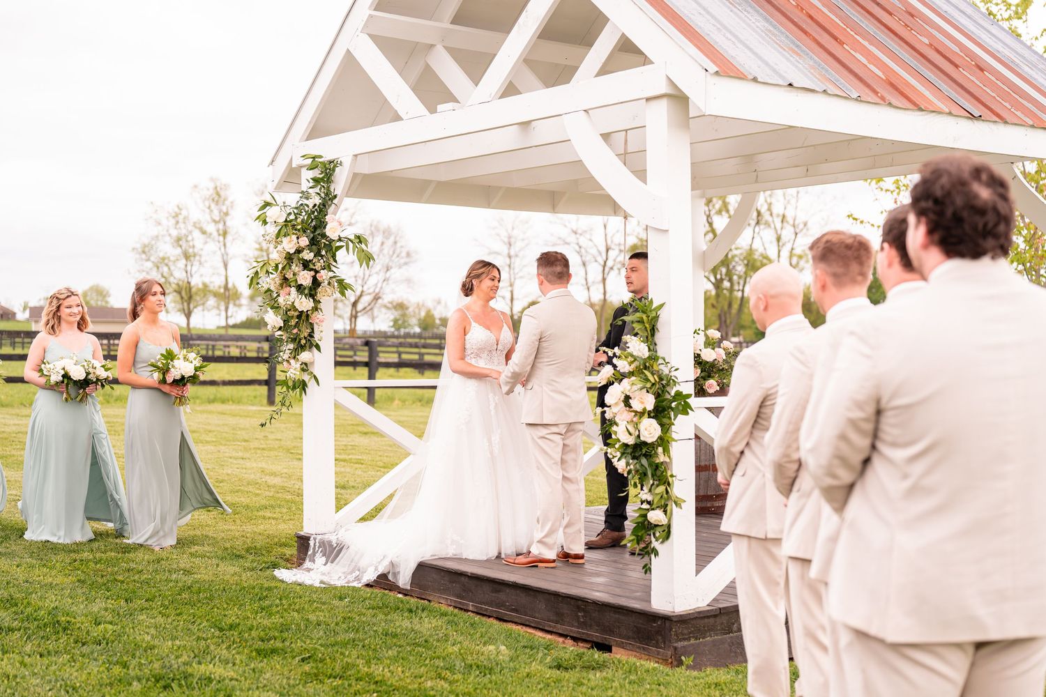 Elegant outdoor wedding ceremony setup with white chairs and floral decorations.