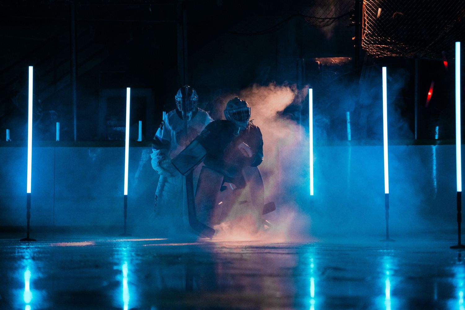 Blue lighting effects illuminate a dark hockey arena with fog effects.