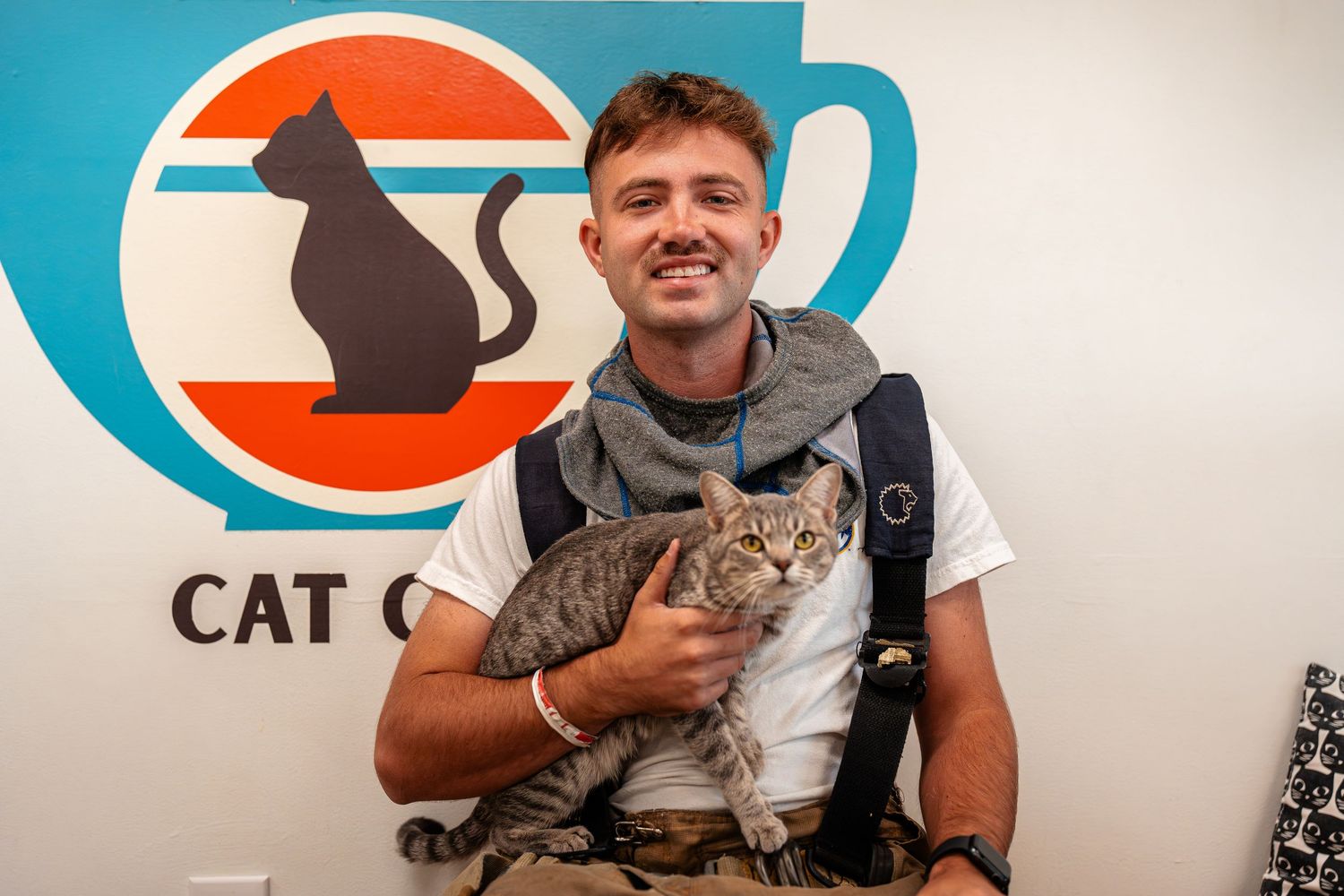 A cat sits calmly next to emergency response equipment with a blue logo in background.